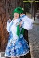 A woman with green hair standing next to a tree.