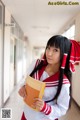 A woman in a school uniform holding a book.