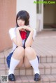 A woman in a school uniform sitting on some steps.