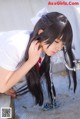 A woman in a school uniform drinking water from a faucet.