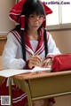 A woman in a red and white uniform sitting at a desk.