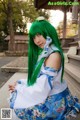 A woman with long green hair wearing a blue and white dress.