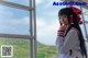 A woman in a school uniform standing by a window.