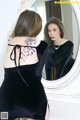 A woman in a black dress looking at herself in the mirror.