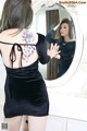 A woman in a black dress looking at herself in the mirror.