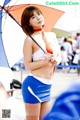 A woman in a blue and white outfit holding an umbrella.