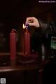 A person lighting a red candle on a table.