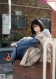 A woman sitting on a brick wall reading a book.