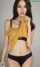 A woman in a yellow top and black panties posing for a picture.