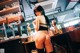 A woman in a black lingerie standing in front of a bar.