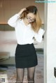 a woman in a white shirt and black skirt posing for a picture