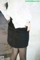 A woman in a white shirt and black skirt.