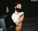 A woman wearing a black face mask and a white shirt.