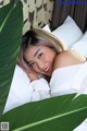 A woman laying in bed with a large green leaf.