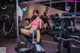 A woman wearing a face mask sitting on a bench in a gym.