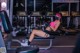 A woman wearing a face mask sitting on a bench in a gym.