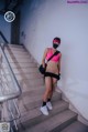 A woman in a pink top and black shorts standing on some stairs.