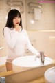 A woman standing in front of a bathroom sink.