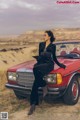 A woman sitting on top of a red convertible car.