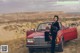 A woman sitting on top of a red convertible car.