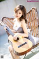 A woman sitting on a chair playing a guitar.