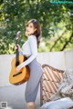 A woman holding a guitar sitting on a chair.