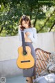 A woman holding a guitar while standing next to a couch.