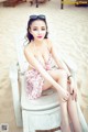 A woman sitting on a white chair on a beach.