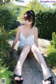 A woman in a white top and black sandals sitting on the ground.