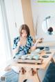 A woman sitting at a table with bowls and cups on it.