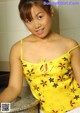 A woman in a yellow top is posing for a picture.