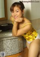 A woman in a yellow top and white panties posing in a bathroom.