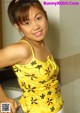 A young woman in a yellow top posing for a picture.