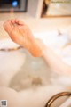 A person's feet in a bathtub filled with foam.