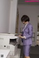 A woman in a purple suit standing next to a printer.