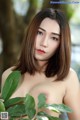 A naked asian woman holding a green leaf in her hand.