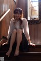 A woman sitting on the steps of a wooden building.