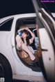 A woman sitting in the driver's seat of a white car.