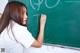 A young woman writing on a blackboard in a classroom.