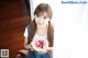 A young woman holding a slice of watermelon with a spoon.