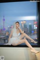 A woman in a wedding dress sitting on a window sill.