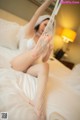 A woman in fishnet stockings is sitting on a bed.