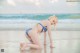 A woman in a bikini kneeling on the beach.