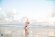 A woman in a bikini sitting on the beach.