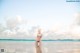 A woman in a bikini sitting on the beach.