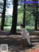 A woman sitting on top of a tree stump in a park.