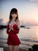 A woman in a red dress standing on a beach.