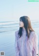 A woman standing on a beach next to the ocean.