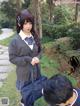 A woman in a school uniform holding a blue bag.