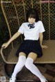 A woman in a school uniform sitting on a chair.